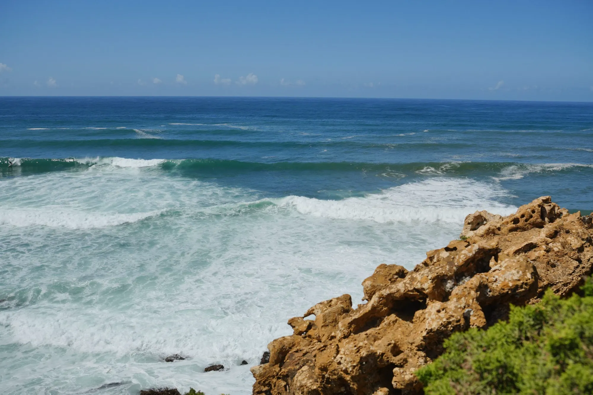 Waves breaking below golden sandstone rocks