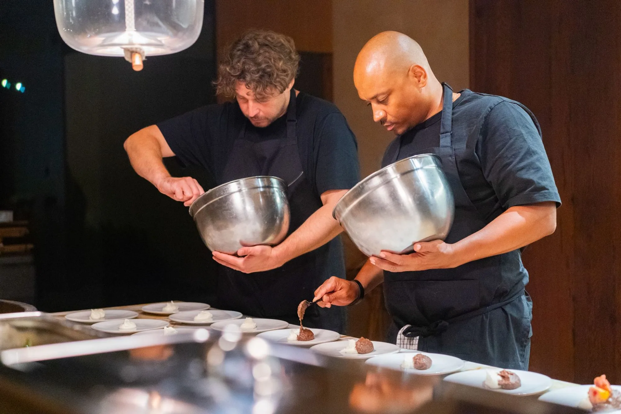 Two chefs plating dessert at the kitchen island