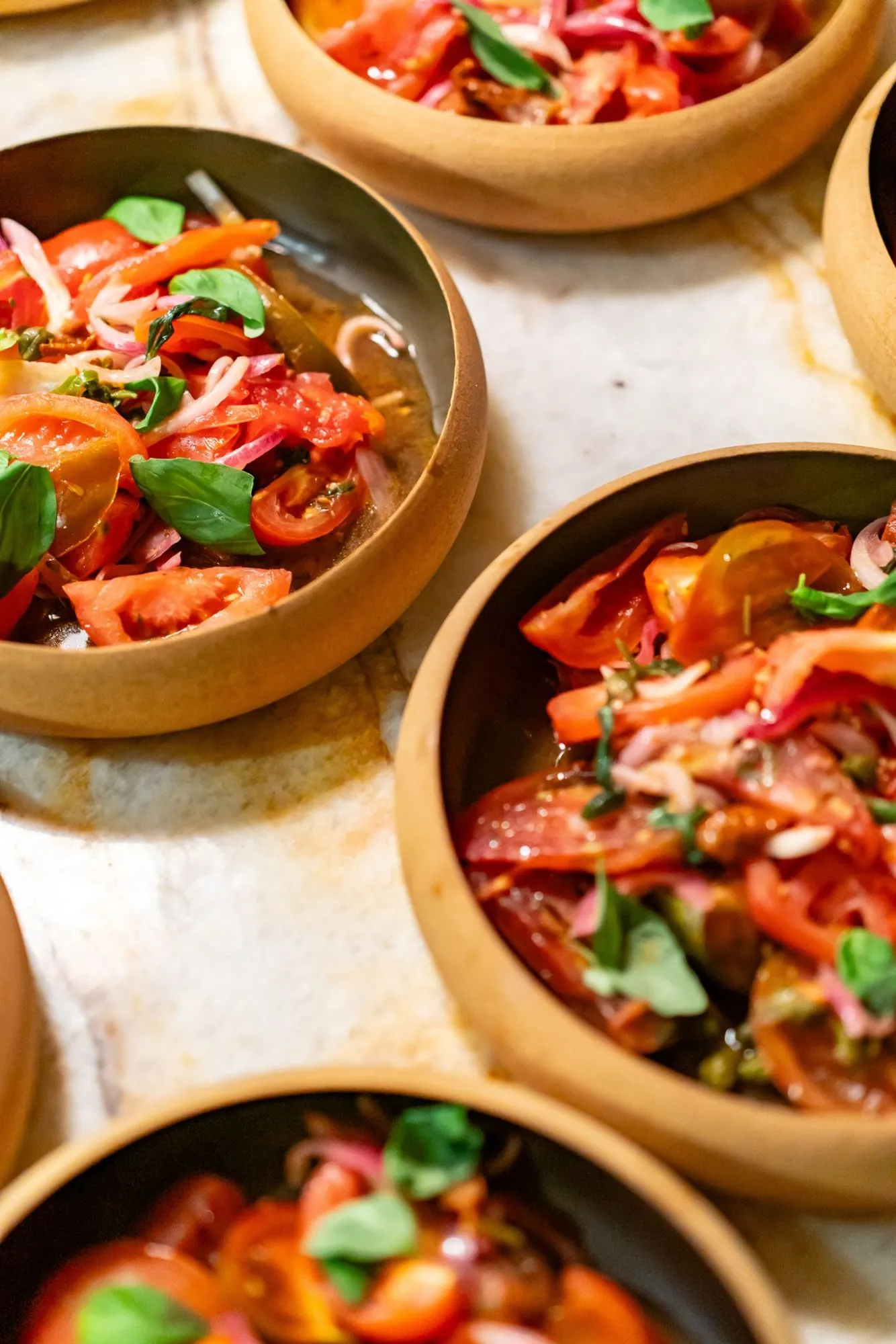 Bowls of tomato salad with basil and pickled onion