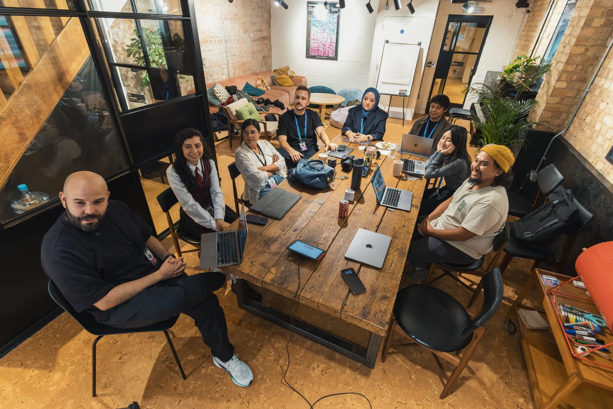 A team gathered round a long wooden table with laptops open
