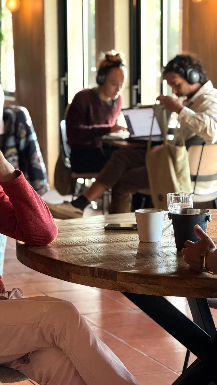 Coffee and conversation at a round wooden table while others work in the background