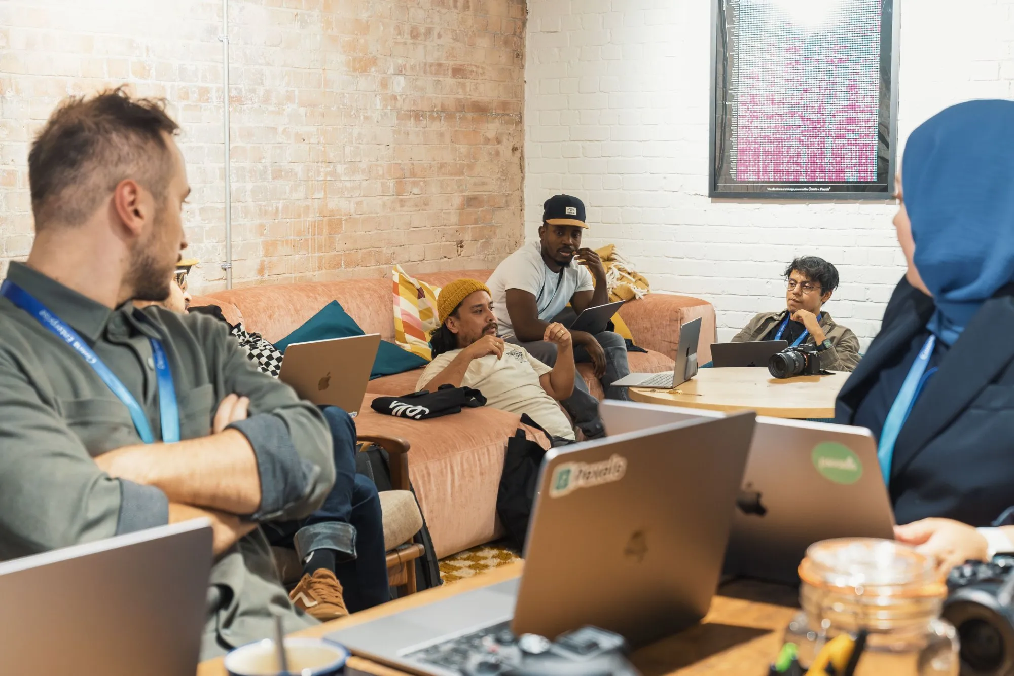 A small group talking on a sofa with laptops